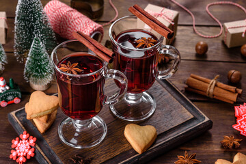 Christmas mulled red wine with spices and fruits on a dark table.