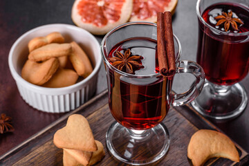 Christmas mulled red wine with spices and fruits on a dark table.