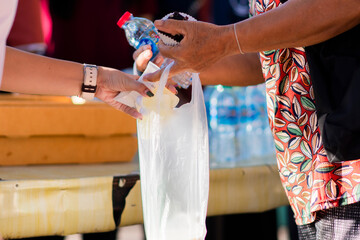 A person putting things in a plastic bag that another person is holding.