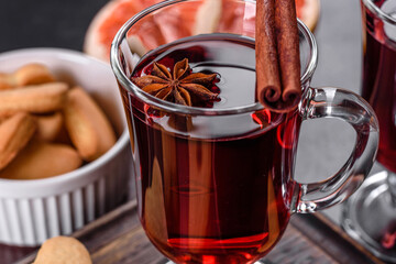 Christmas mulled red wine with spices and fruits on a dark table.