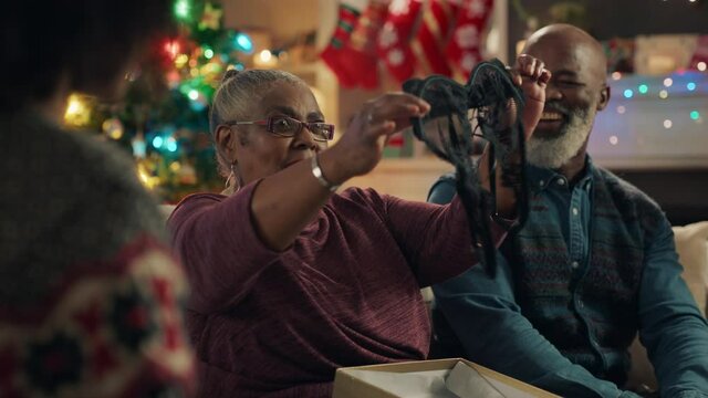 african american grandmother opening christmas gift with surprise sexy bra laughing enjoying funny joke with family celebrating festive holiday at home 4k