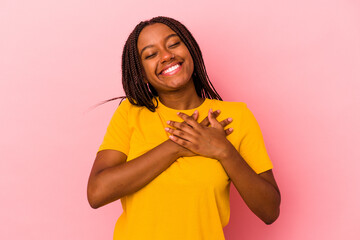 Young african american woman isolated on pink background  has friendly expression, pressing palm to chest. Love concept.