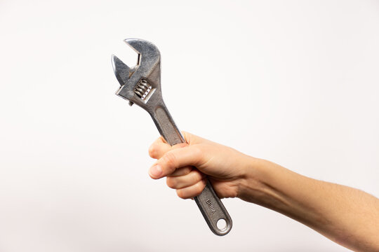 Mano sosteniendo herramienta, llave alemana. Fondo blanco. 