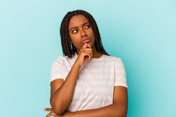 Young african american woman isolated on blue background  thinking and looking up, being reflective, contemplating, having a fantasy.