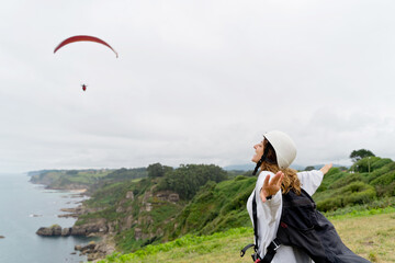 Horizontal view of caucasian woman with paragliding equipment on a cliff. Panoramic view of...