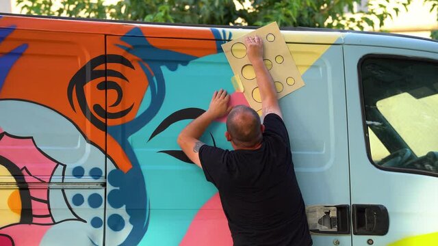 international artist day. graffiti artist preparing stencil for painting van