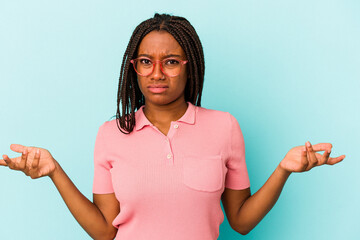 Young african american woman isolated on blue background  doubting and shrugging shoulders in...