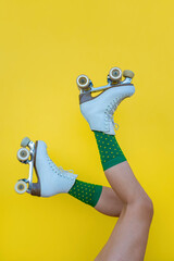 Woman with vintage quad roller skates and green socks on yellow background