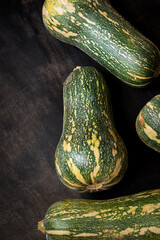 Fresh and green elongated pumpkin on a black wooden table