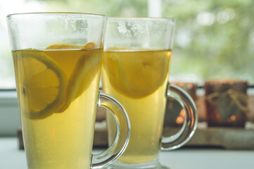 Close-up of couple of glasses with vitamin green tea with lemon and orange. Candles on background. Healthy hot drink.