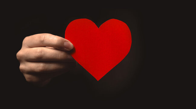 Hand holding paper heart on black background. Health insurance, organ donor day, charity. World health day, world mental health day, world heart day, gratitude and all lives matter background photo