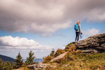 Woman with backpack and camera climbing at mountain peak. Hiking and adventure concept. Outdoors...