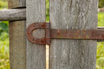 Old rusty metal door hinge. Iron door hinge on a wooden fence.