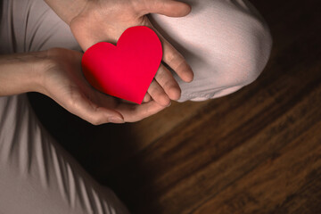Fototapeta premium Hands giving red heart. Concept of giving love. Healthcare, life insurance, mental health banner. Black background, banner with copy space photo