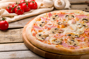 Pizza with ham and mushrooms on old wooden table close up macro