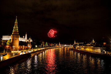 Naklejka premium fireworks over the night river with floating motor ships of the embankment and the old Kremlin 