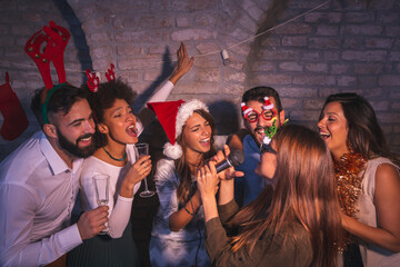 Friends dancing and singing karaoke at New Year's Eve party