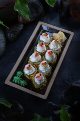 Rolls in tempura with mussels. Traditional Japanese cuisine. Raspberry tobik caviar. Ebi tempura. White ginger. Cocktail shrimp. Vertical photo on black background.Top view.