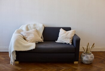 Comfortable little IKEA couch with white pillows and throw