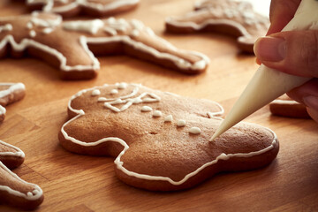Decorating homemade gingerbread Christmas cookies with white icing using a cone