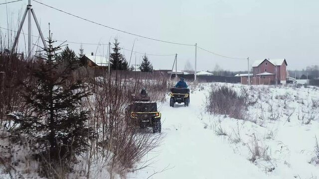 Men ride ATVs on a snowy road