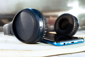 Fototapeta na wymiar Wireless blue headphones and and blue mobile phone close up 
