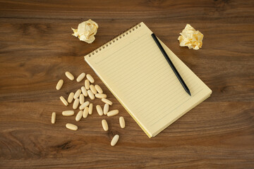 suicide note. Notepad, pen and pills on a wooden background. Top view, close-up.