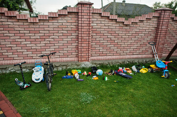 Different toys and bycicles at grass on home.