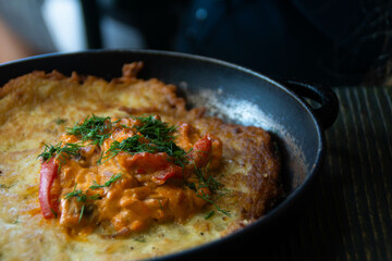 A pan with a huge potato pancake and stewed vegetables