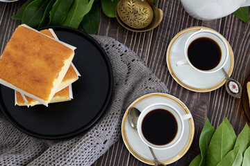 coffee in white cup on white porcelain plate on wooden table.