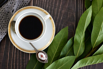 coffee in white cup on white porcelain plate on wooden table.