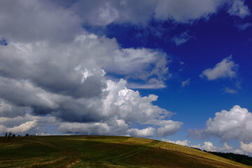 hill with different green from the grass and amazing clouds on the blue sky