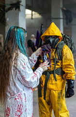 Doctor in bloody coat gives bottle of blood to man in biological protection suit and gas mask with rifle