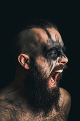 Portrait of a Viking warrior with black war paint, screaming with rage and anger