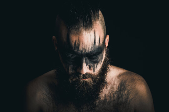 Viking warrior with black war paint looking down in despair and defeat 