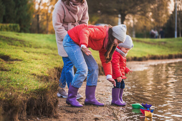child playing with paper boats in spring water.lake or river