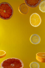 A closeup shot of orange and grapefruit slices against a yellow background