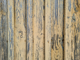 Wooden planks stacked vertically on top of each other with a row of nails, cracked yellow paint and a worn background texture. Vintage texture, pattern