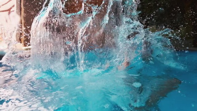 Pool jump. Preteen boy jumps into the swimming pool with splashes and underwater splitted view