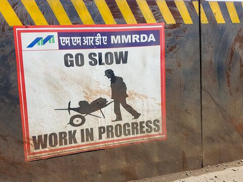 A Go Slow Work in Progress signboard warning vehicles at a road construction site in Mumbai.