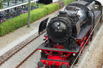 Obraz premium Old historic steam black locomotive with red wheels at station Dieren in the Netherlands