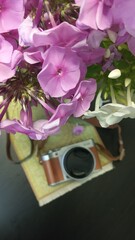 The camera lies on the table next to a bouquet of flowers