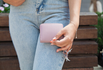 Woman standing on the street holding wallet.
