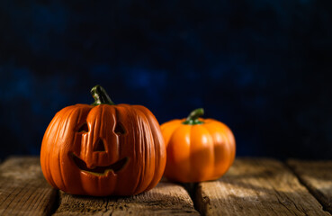 Halloween background. Two pumpkins against a dark blue night sky. One pumpkin in the form of a head. Wooden texture. Halloween celebration, invitation, postcard, advertisement.