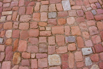 Vintage cobblestone pavement. Stone paved red road