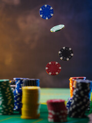 Casino. Poker game. Colored chips lie on the green cloth of the poker table. Some of them are in a state of levitation. Dark background. There is no one in the photo. Focusing on the foreground.