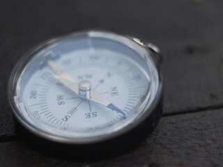 the magnetic compass lies on a wooden surface. the compass indicates the direction