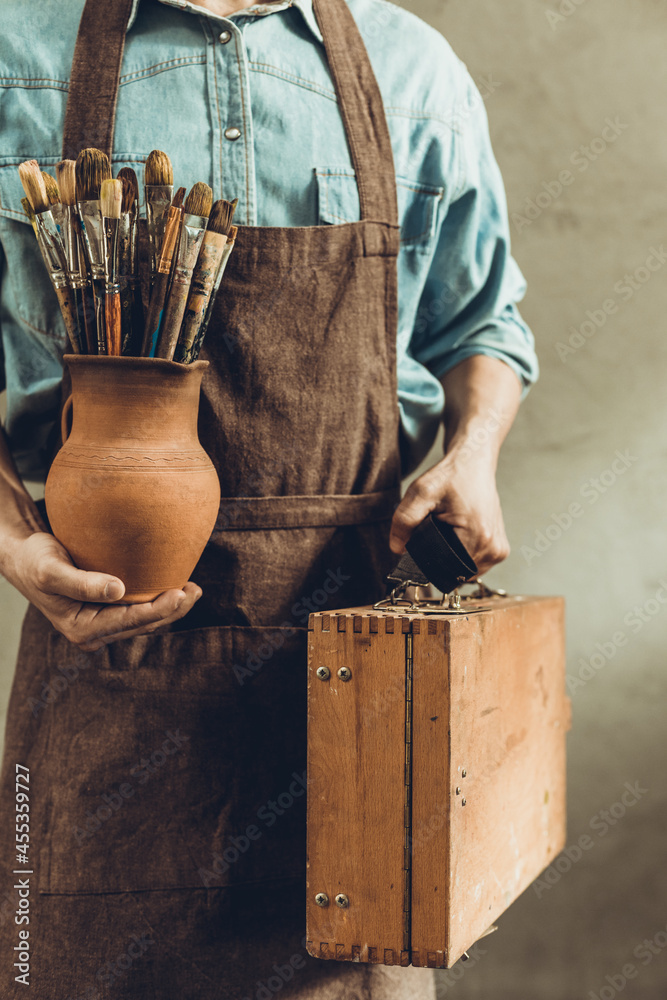 Poster man artist painter holding clay jug with paint brush. painter artist and paintbrush in studio