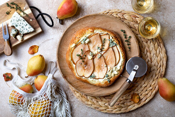 Pizza with pear, thyme, ricotta and blue cheese on  wooden board and wine glasses