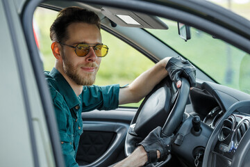 Portrait of a young man in dark glasses driving a car